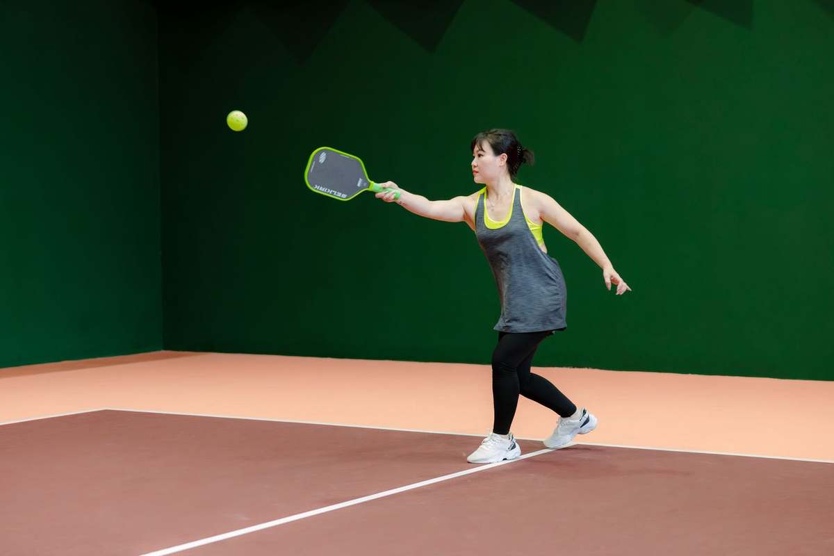 Player hitting a pickleball inside an indoor sports hall court