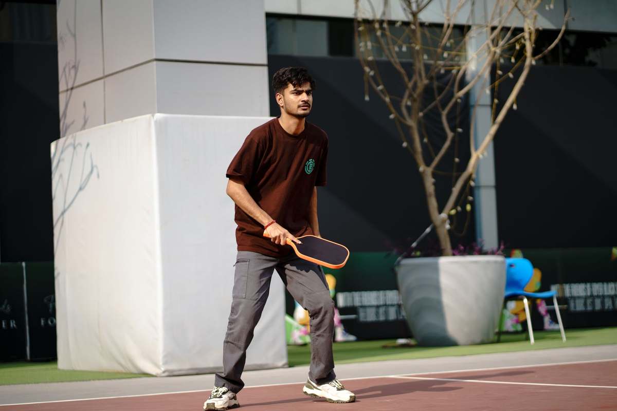 Player hitting a pickleball on an outdoor resort court with painted lines
